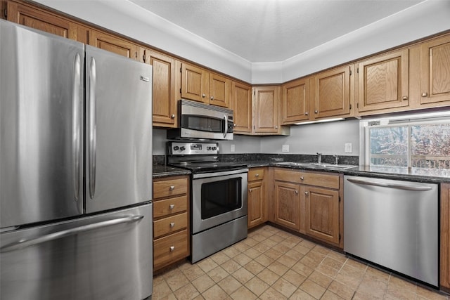 1156 Cambria Ct, Iowa City, IA 52246 - kitchen featuring appliances with stainless steel finishes, dark stone countertops, brown cabinetry, and a sink