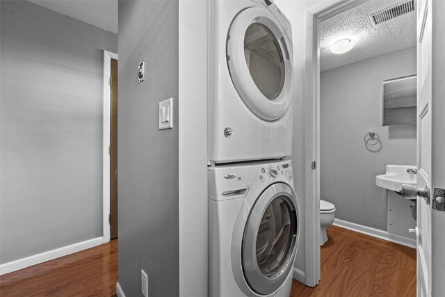 1156 Cambria Ct, Iowa City, IA 52246 - laundry area featuring wood finished floors, laundry area, visible vents, stacked washer and clothes dryer, and a textured ceiling