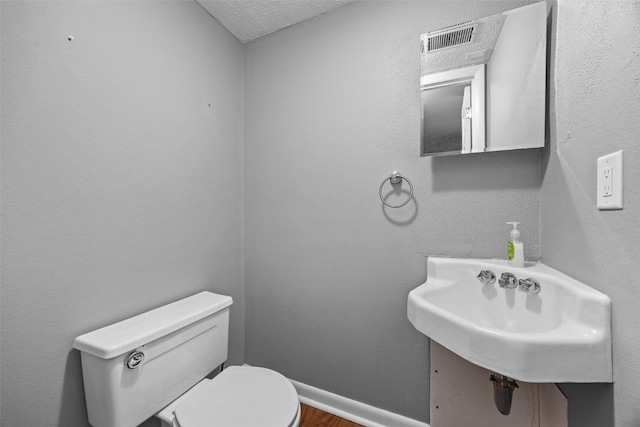 1156 Cambria Ct, Iowa City, IA 52246 - bathroom featuring a sink, toilet, visible vents, a textured ceiling, and wood finished floors