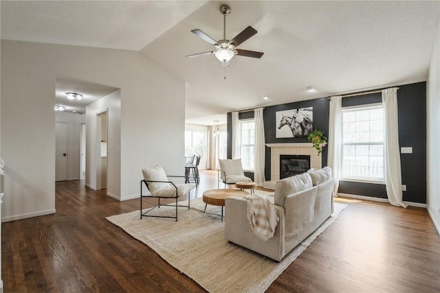 1835 Valentine Dr, Marion, IA 52302 - living area featuring a ceiling fan, wood finished floors, a tile fireplace, vaulted ceiling, and plenty of natural light