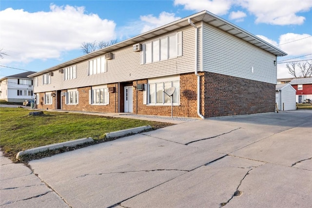 3212 Wilson Ave SW, Cedar Rapids, IA 52404 - view of front of property featuring brick siding, a front yard, a wall mounted AC, and concrete driveway