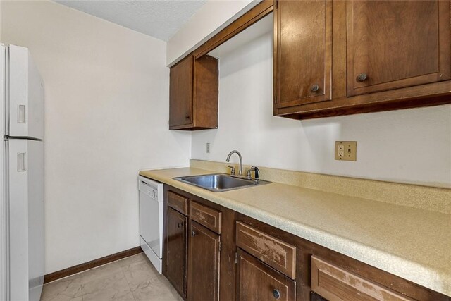 3212 Wilson Ave SW, Cedar Rapids, IA 52404 - kitchen featuring a sink, white appliances, light marble finish floors, light countertops, and baseboards