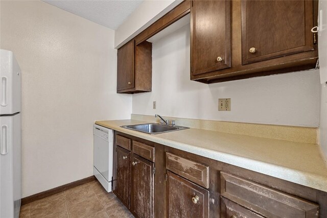 3212 Wilson Ave SW, Cedar Rapids, IA 52404 - kitchen with white appliances, a sink, dark brown cabinets, light countertops, and baseboards