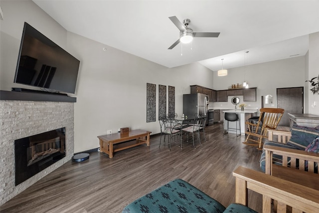 living room featuring a fireplace, a ceiling fan, high vaulted ceiling, and dark wood finished floors