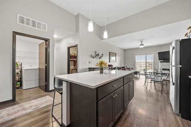 kitchen with washer / clothes dryer, visible vents, ceiling fan, freestanding refrigerator, and wood finished floors