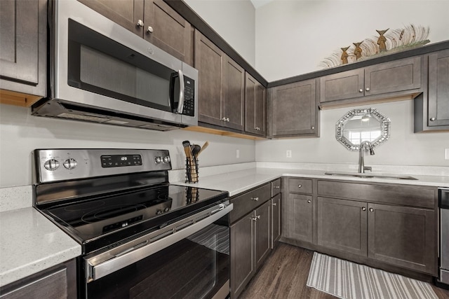 kitchen featuring dark wood finished floors, dark brown cabinets, appliances with stainless steel finishes, and a sink