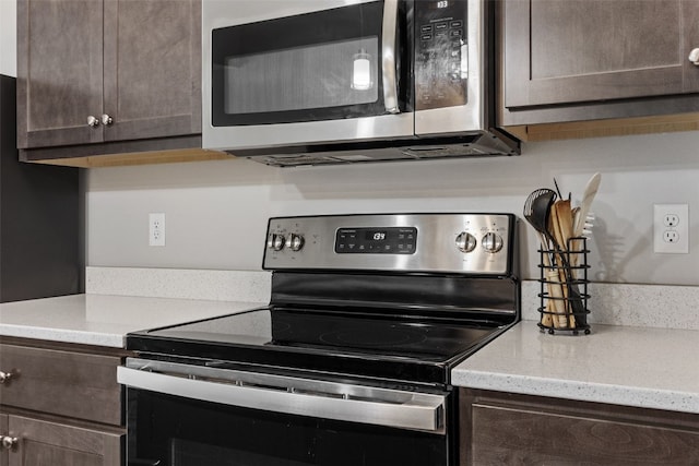 kitchen featuring light stone countertops, stainless steel appliances, and dark brown cabinets