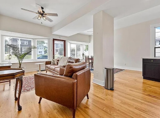 living room with a ceiling fan, baseboards, and light wood-type flooring