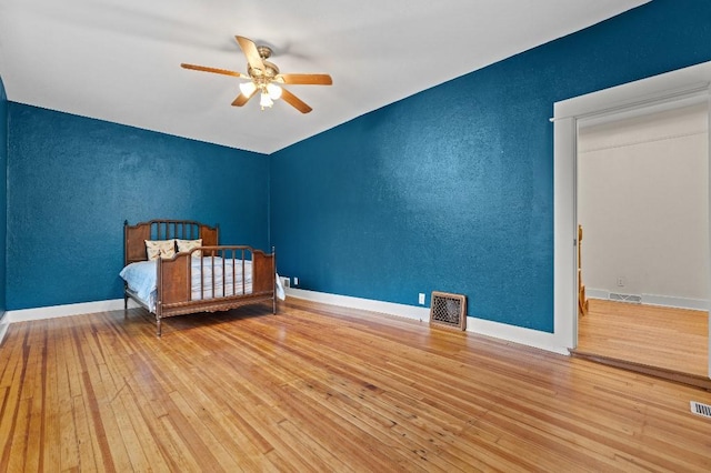 unfurnished bedroom with hardwood / wood-style floors, a textured wall, ceiling fan, and visible vents