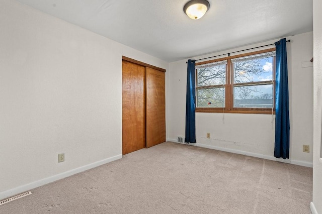 unfurnished bedroom with a closet, visible vents, carpet floors, and baseboards