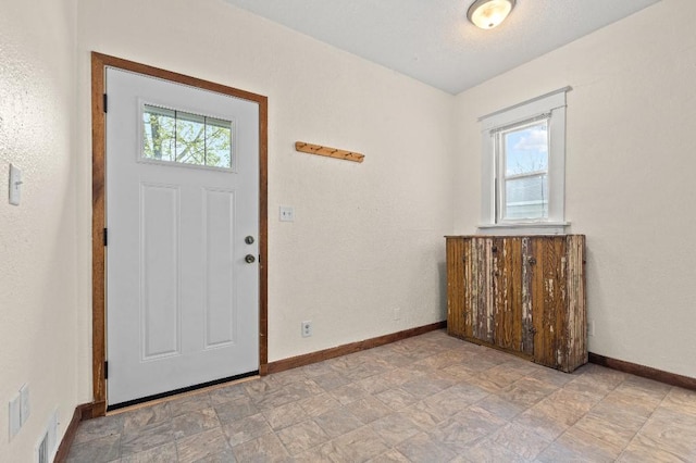 foyer entrance featuring stone finish floor and baseboards