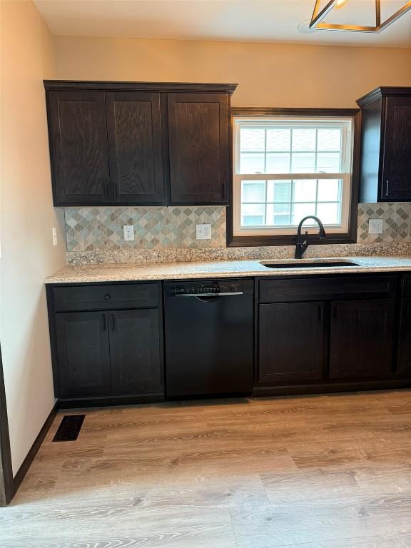 305 E 5th St, Vinton, IA 52349 - kitchen with light wood finished floors, a sink, decorative backsplash, black dishwasher, and visible vents