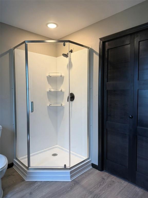 305 E 5th St, Vinton, IA 52349 - bathroom featuring wood finished floors, toilet, and a shower stall