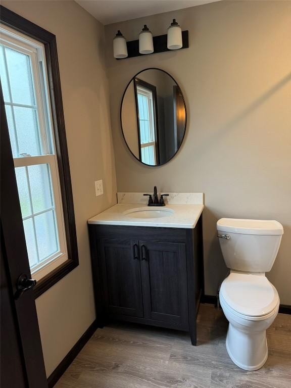 305 E 5th St, Vinton, IA 52349 - bathroom with baseboards, wood finished floors, a wealth of natural light, and vanity