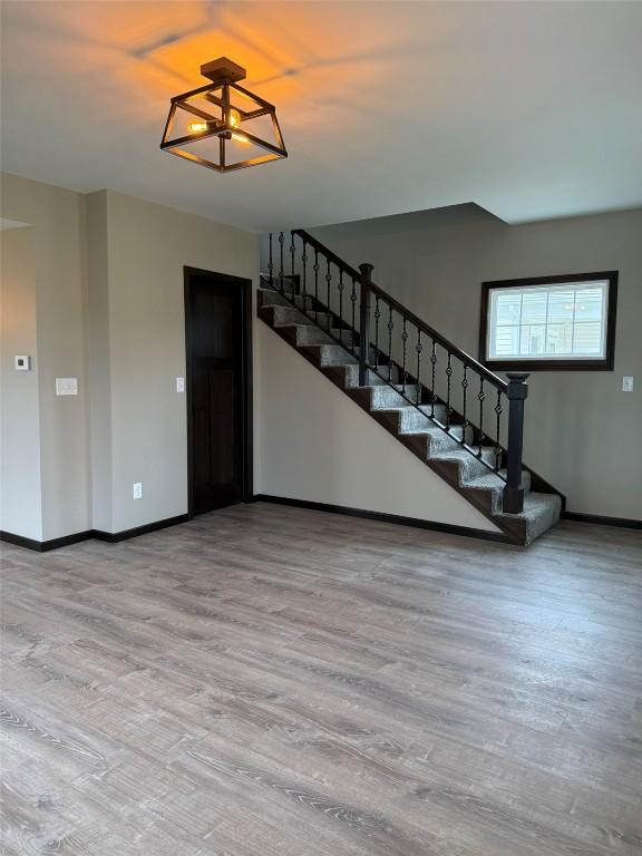 305 E 5th St, Vinton, IA 52349 - unfurnished living room featuring baseboards, wood finished floors, and stairs