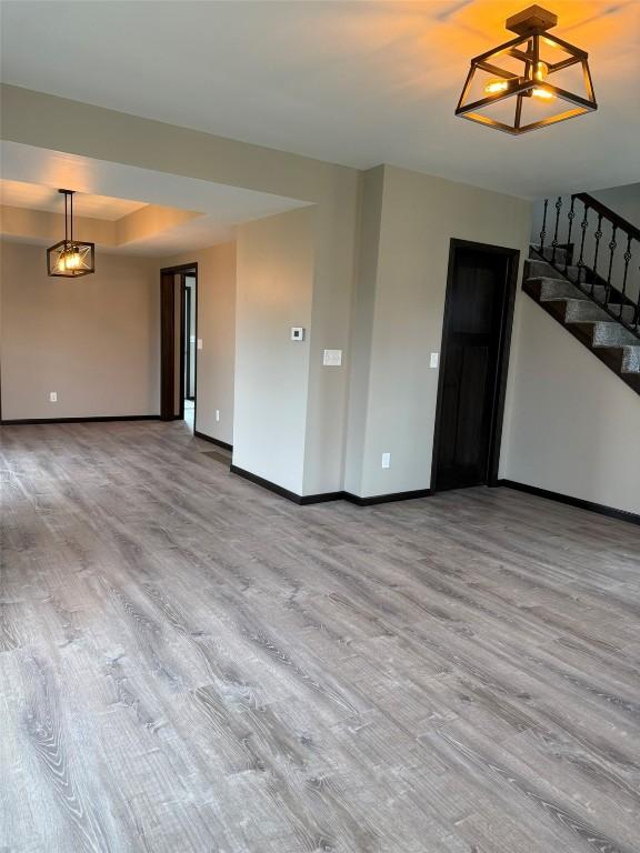 305 E 5th St, Vinton, IA 52349 - unfurnished living room featuring stairs, a chandelier, wood finished floors, and baseboards