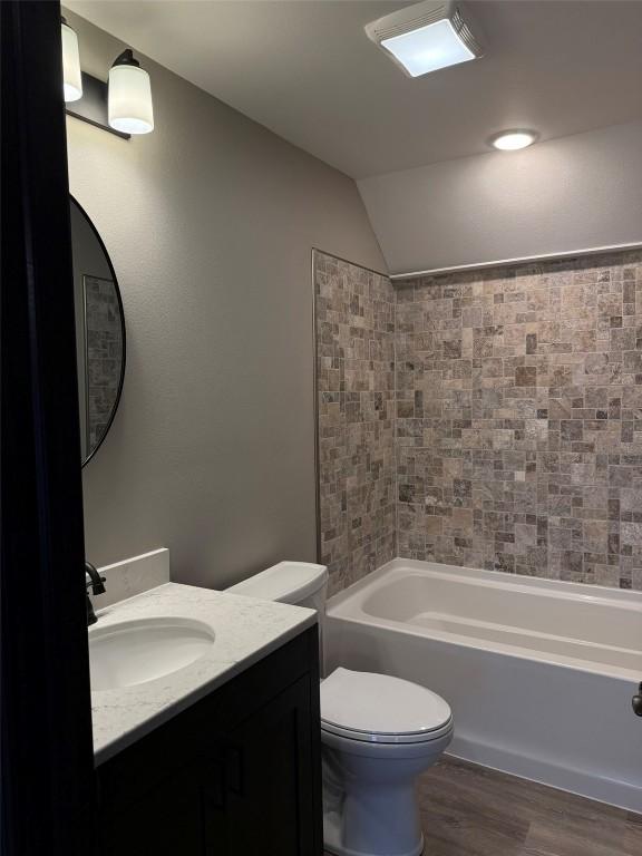 305 E 5th St, Vinton, IA 52349 - bathroom with vanity, wood finished floors, toilet, shower / washtub combination, and lofted ceiling