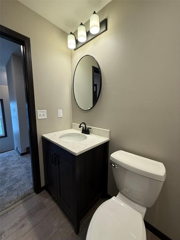 305 E 5th St, Vinton, IA 52349 - bathroom with toilet, vanity, and wood finished floors