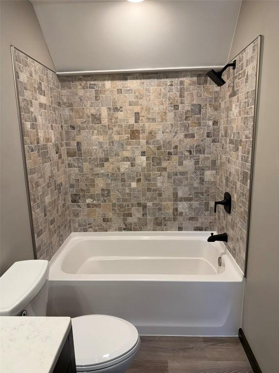 305 E 5th St, Vinton, IA 52349 - bathroom with wood finished floors, vanity, toilet, and vaulted ceiling