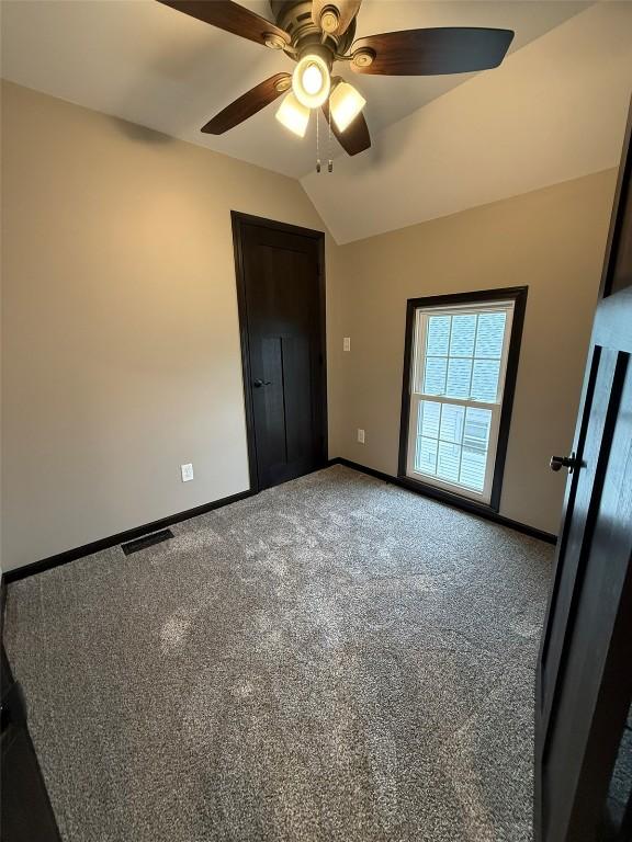 305 E 5th St, Vinton, IA 52349 - unfurnished bedroom with a ceiling fan, visible vents, vaulted ceiling, carpet, and baseboards