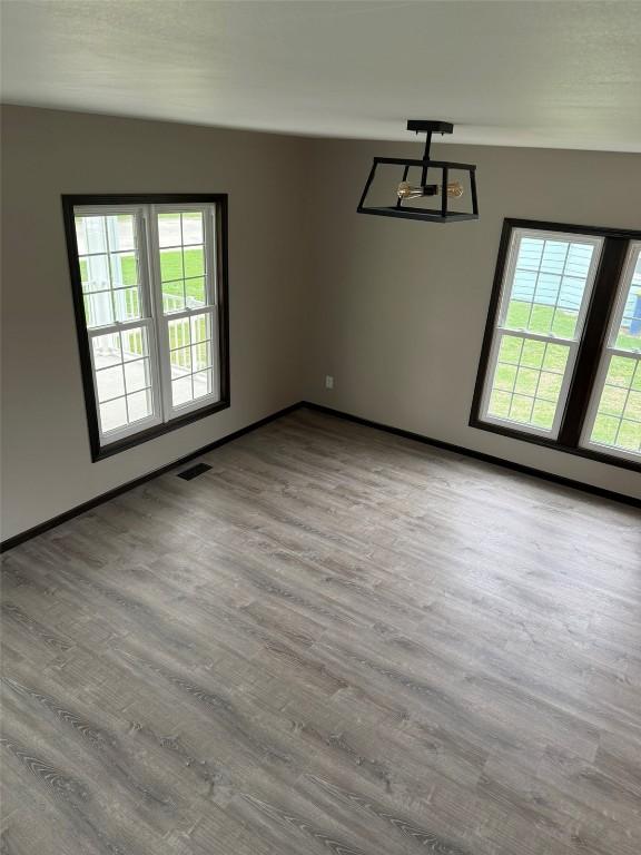 305 E 5th St, Vinton, IA 52349 - empty room with wood finished floors, visible vents, and baseboards