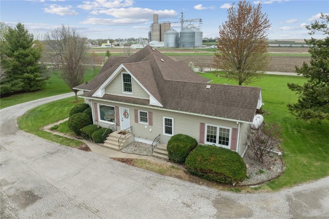 view of front facade with a front yard and a shingled roof