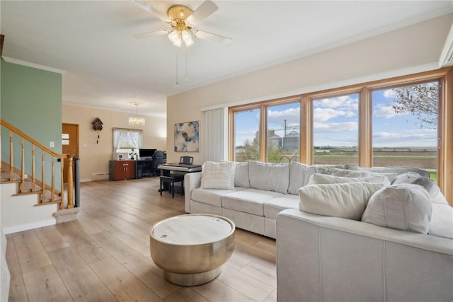 living room featuring stairway, a baseboard heating unit, ceiling fan, baseboards, and light wood-type flooring