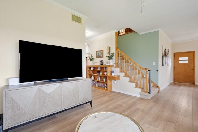 living area featuring wood finished floors, visible vents, crown molding, and stairs