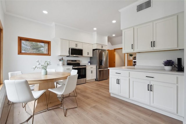 kitchen with white cabinetry, crown molding, visible vents, stainless steel appliances, and light wood-type flooring