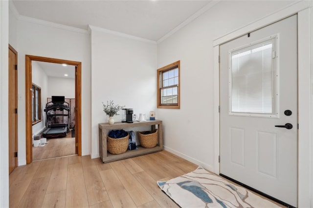 foyer featuring light wood-style floors, ornamental molding, and baseboards