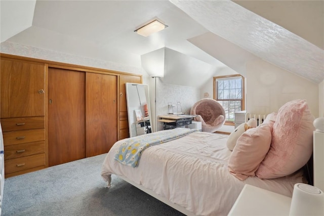 carpeted bedroom with a closet and vaulted ceiling