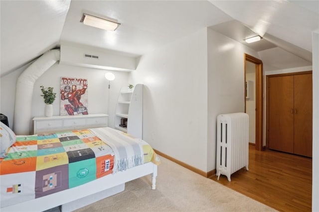 bedroom with lofted ceiling, radiator heating unit, visible vents, and baseboards