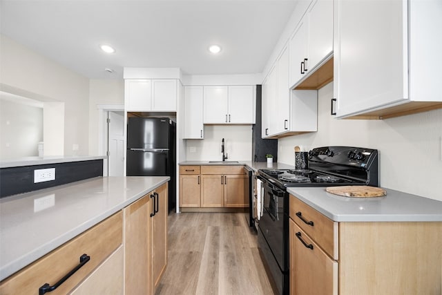 317 16th St NE, Cedar Rapids, IA 52402 - kitchen featuring black appliances, a sink, light wood-style flooring, light countertops, and white cabinets
