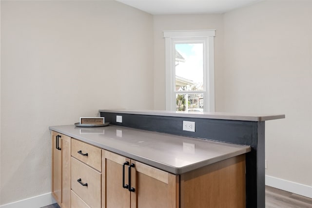 317 16th St NE, Cedar Rapids, IA 52402 - kitchen featuring light brown cabinets, baseboards, light wood-style flooring, a peninsula, and light countertops