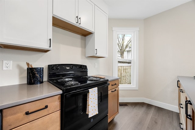 317 16th St NE, Cedar Rapids, IA 52402 - kitchen with black electric range oven, dark wood-style flooring, baseboards, white cabinets, and light countertops