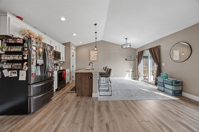 5116 Ruhd St SW, Cedar Rapids, IA 52404 - kitchen with refrigerator with ice dispenser, stainless steel microwave, black electric range oven, light wood finished floors, and lofted ceiling
