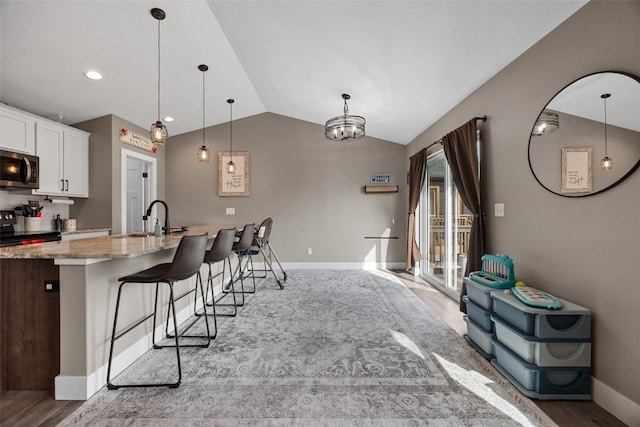 5116 Ruhd St SW, Cedar Rapids, IA 52404 - kitchen with light stone counters, a sink, stainless steel microwave, vaulted ceiling, and range with electric stovetop