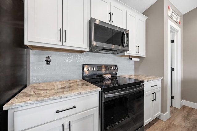 5116 Ruhd St SW, Cedar Rapids, IA 52404 - kitchen featuring stainless steel microwave, electric range, freestanding refrigerator, light wood finished floors, and white cabinetry