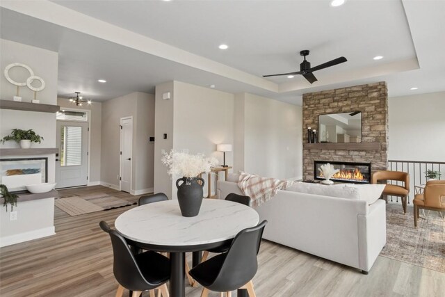 3125 Sunflower St, Ely, IA 52227 - dining room featuring a fireplace, a raised ceiling, light wood-style flooring, ceiling fan, and recessed lighting