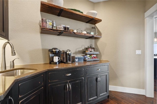 bar featuring baseboards, dark wood-style floors, and a sink