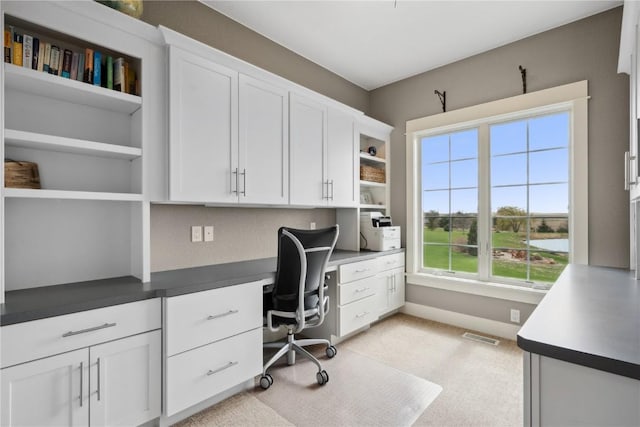 home office featuring built in desk, visible vents, light colored carpet, and baseboards