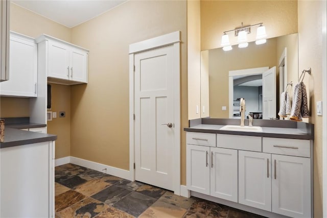 bathroom featuring baseboards, stone finish flooring, and vanity
