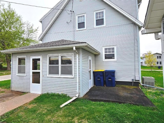 rear view of property featuring a lawn, central AC unit, and a patio area