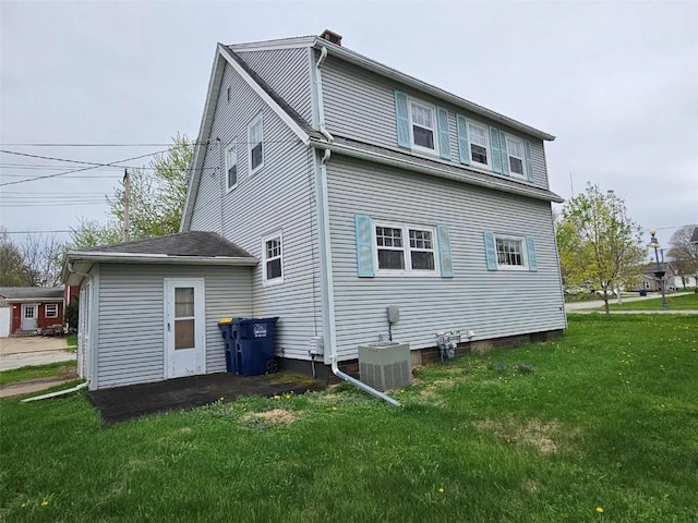 back of property with a yard and central air condition unit