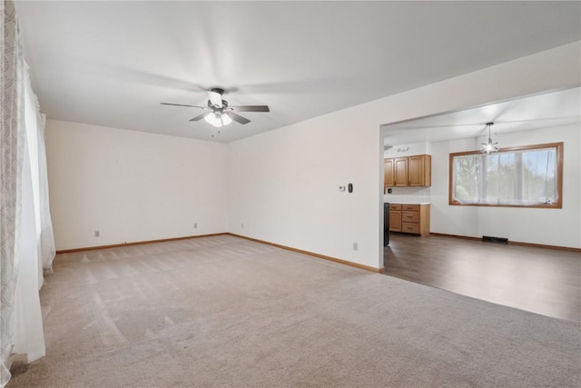 unfurnished living room with baseboards, ceiling fan, visible vents, and light colored carpet