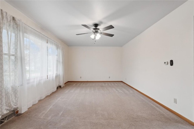 unfurnished room with baseboards, ceiling fan, and light carpet