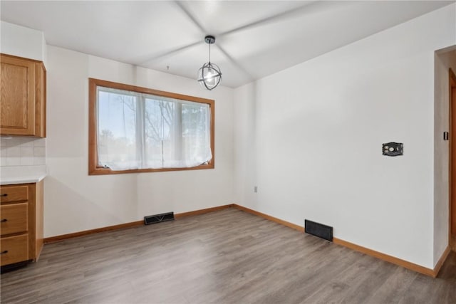 unfurnished dining area with visible vents, baseboards, and wood finished floors