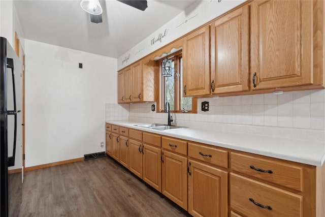 kitchen featuring dark wood-style flooring, a sink, light countertops, freestanding refrigerator, and decorative backsplash