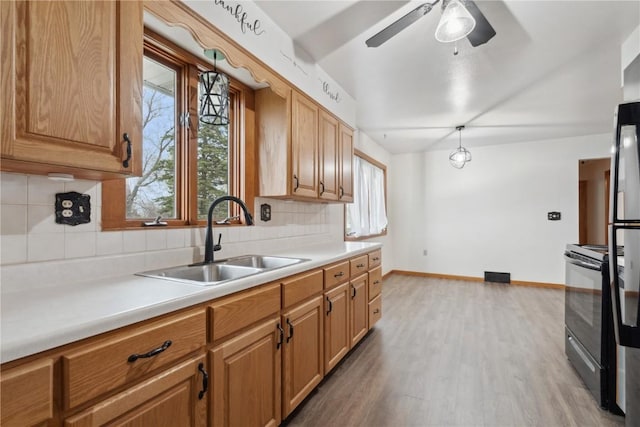 kitchen featuring a sink, tasteful backsplash, black electric range oven, and wood finished floors