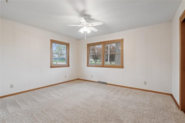 unfurnished room with visible vents, a ceiling fan, baseboards, and carpet floors